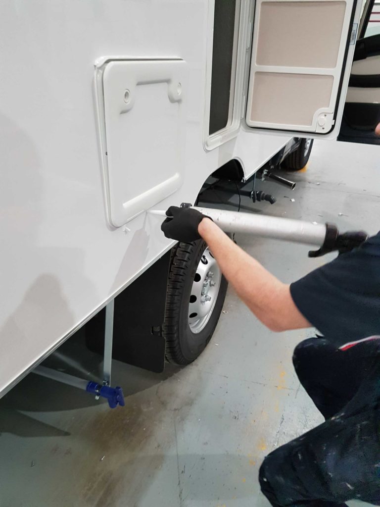 Operative applying adhesive to the panel of a caravan